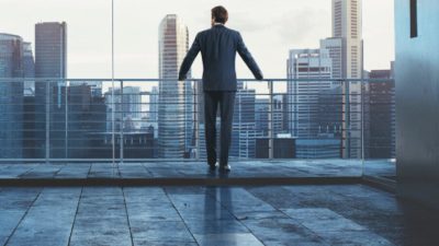 Businessman standing at a railing looking out over a city skyline