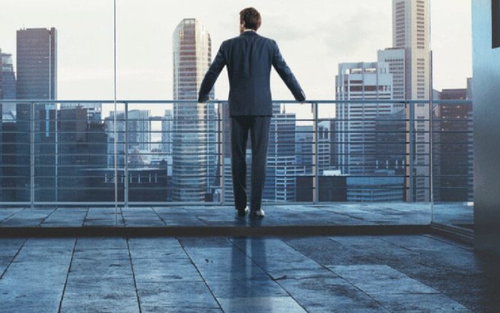 Businessman standing at a railing looking out over a city skyline